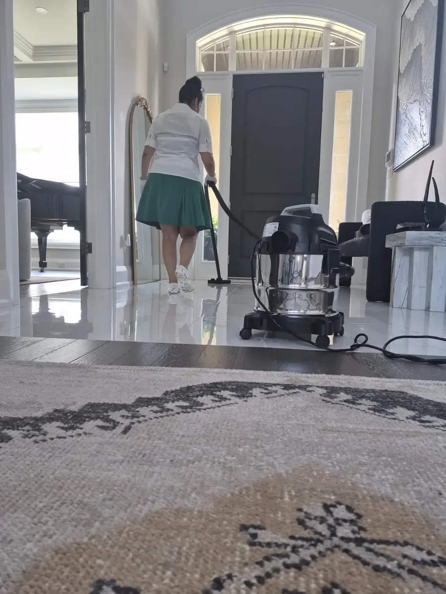 Fresh & Shiny vacuuming beneath a movable front foyer rug during weekly house cleaning in Ajax.