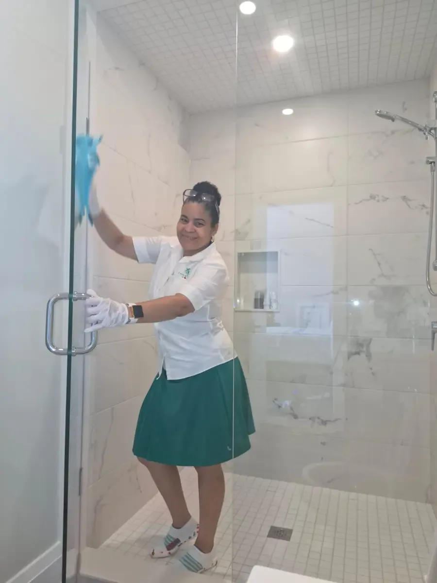 Fresh & Shiny cleaner polishing a glass shower enclosure during weekly bathroom cleaning in Ajax, Ontario.